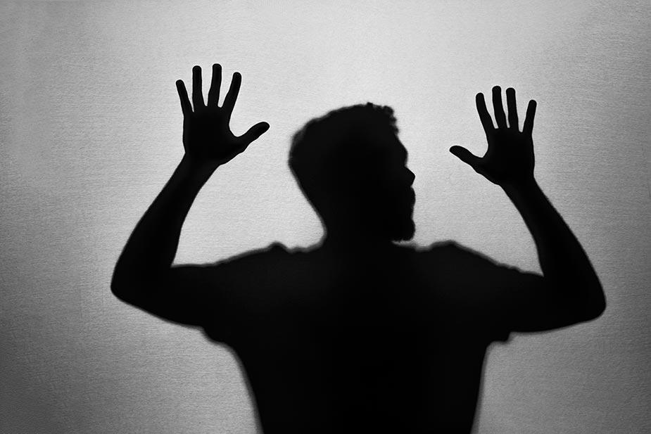 anksioznost - silueta uplašenog mladića sa podignutim i raširenim rukama koji kao da je naleteo na nevidljivi zid