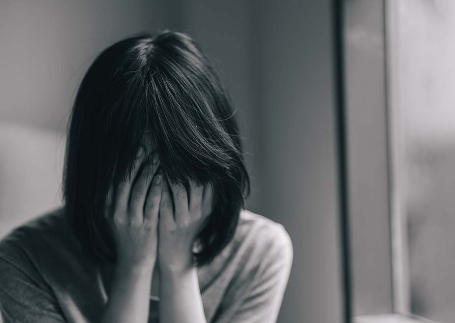 Tužna žena drži glavu rukama - Depersonalizacija i derealizacija
