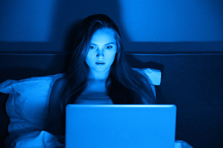 Žena u krevetu gleda u ekran laptopa ne zna da plavo svetlo nije dobro po zdravlje