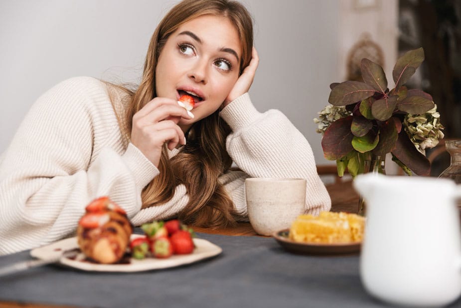 Zamišljena žena nalakćena na sto razmišlja da li će joj smetati hrana koju jede