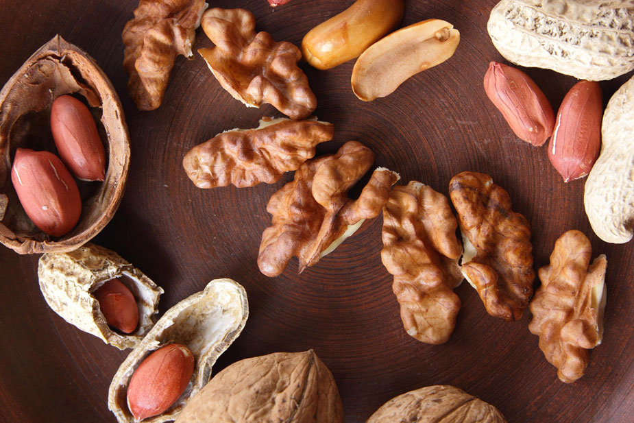 pogled odozgo na sto sa razbacanim orašastim plodovima i kikirikijem