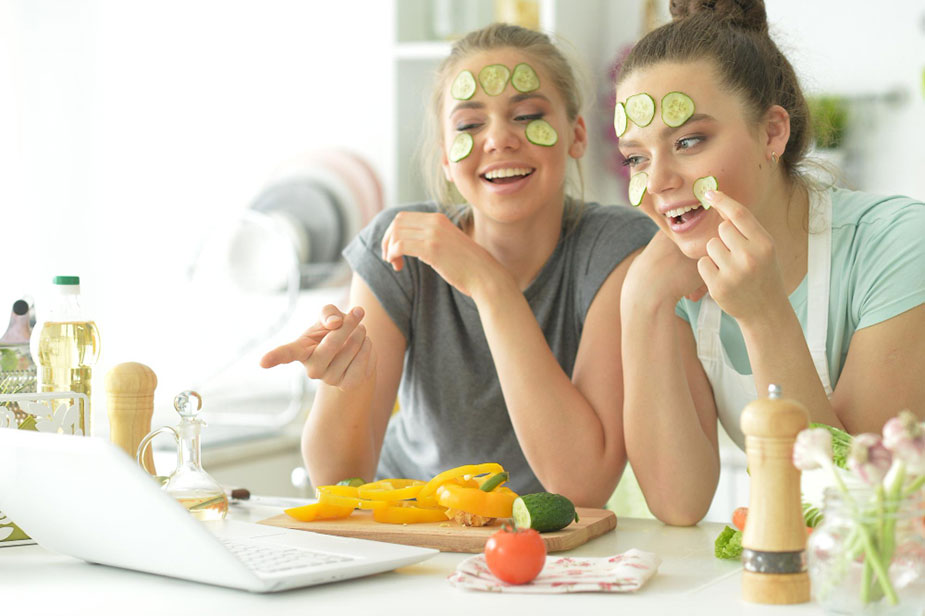 Nasmejane devojke grickaju povrće i gledaju u laptop