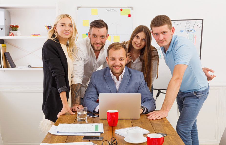 Petoro zaposlenih okupljeni oko stola poziraju za fotografisanje