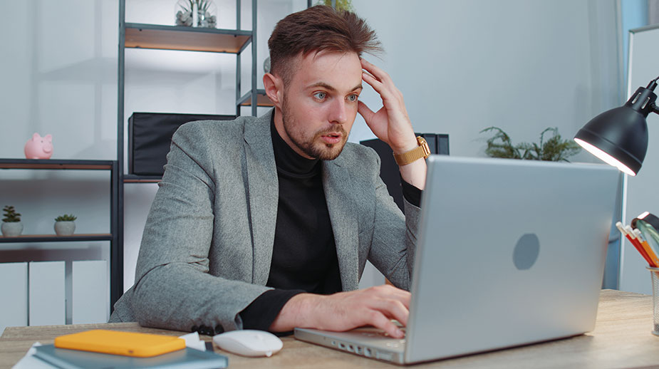 Iznenađen i preopterećen radnik ispred računara – rezultat multitaskinga i preopterećenja informacijama