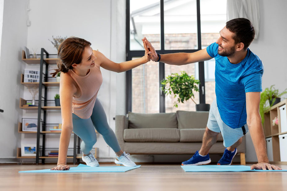 Par daje petice dok zajedno vežbaju kod kuće na prostirkama za vežbanje.
