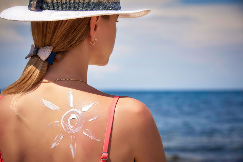  Žena na plaži sa šeširom, gleda u more, spokojna letnja scena