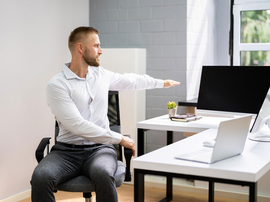 Zaposlena žena sedi za radnim stolom i pravi pauzuzi stavivši ruke iza vrata.