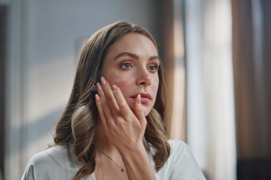 Žena dodiruje lice i proverava kožu koja pecka i zateže se